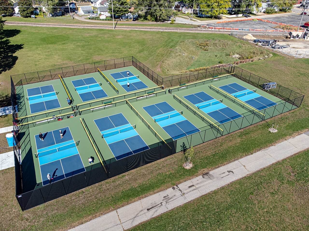 freshly painted pickleball court lines with a measuring tape across the baseline